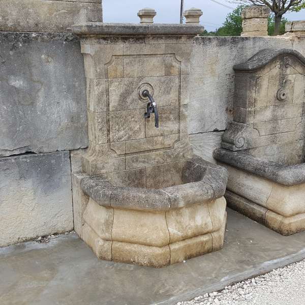 Fontaine ancienne en pierre dorée avec chapeau plat et bec en fer