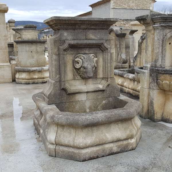 Fontaine ancienne avec tête de bélier sculptée en guise de gargouille