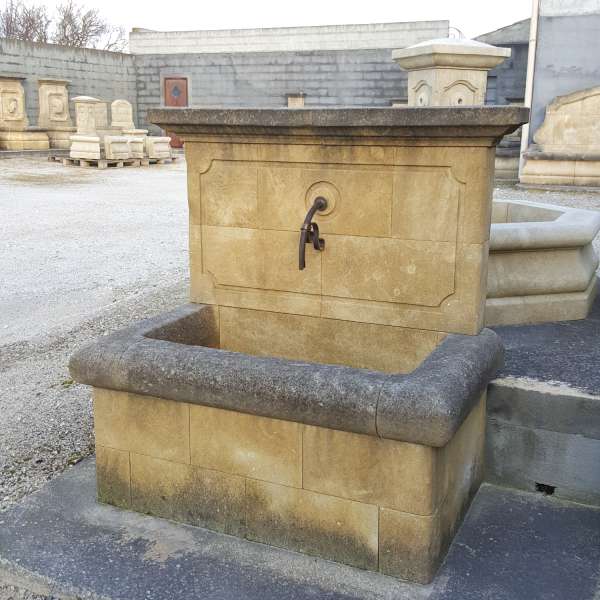Mignonne fontaine ancienne en pierre dorée vieillie de style simple et rustique