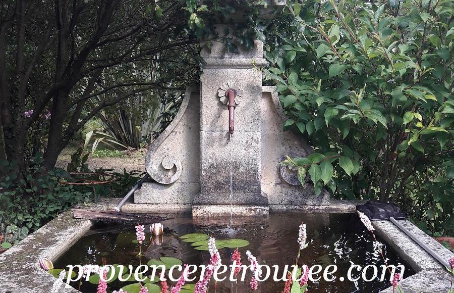 fontaine ancienne en pierre de taille provence retrouvée, installée dans son écrin de verdure et patinée par le temps