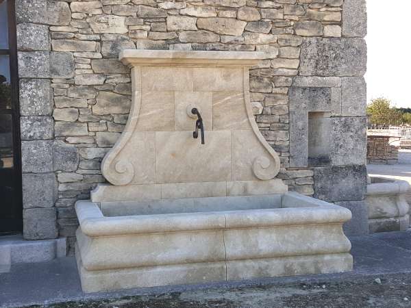 Fontaine murale avec volutes taillées dans la pierre