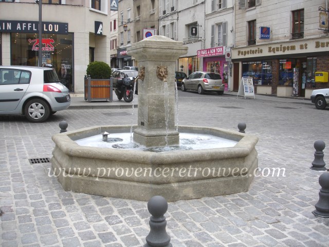 exemple d'une fontaine centrale installée sur une place publique en pavés anciens